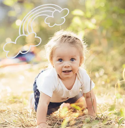 Une petite fille à quatre pattes dans l'herbe, au soleil